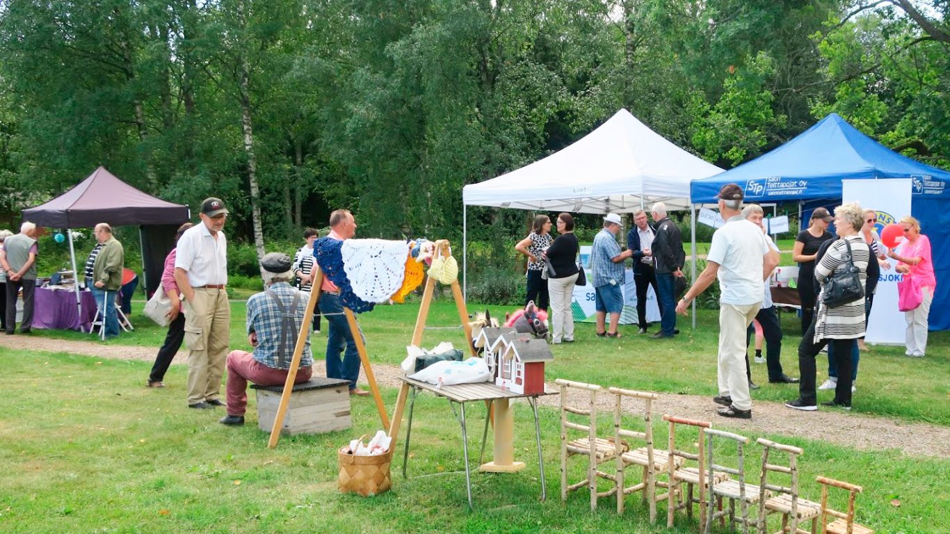 Kuva vuoden 2019 Kuusjoki-päivästä. Taustalla myyntikojuja, edessä ihmisiä. Pilvinen sää.