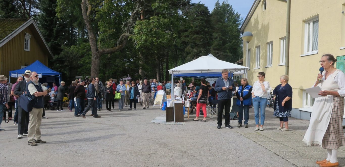 Kuva vuoden 2018 Muurlan Wanhanajan markkinoilta. Kuvassa etualalla ihmisiä ja oikealla Muurlan opiston rakennus. Aurinkoinen ilma.