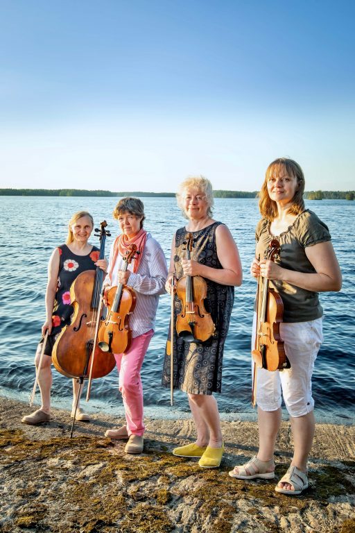 Neljä naista soittimien kanssa meren rannalla