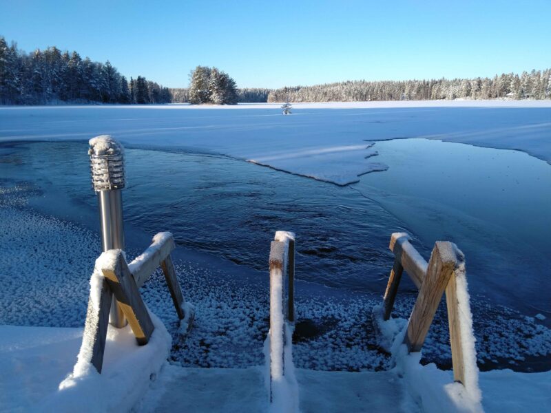 Laineranta ice hole with snowy stairs. Naarjärvi in the background on a sunny winter day.