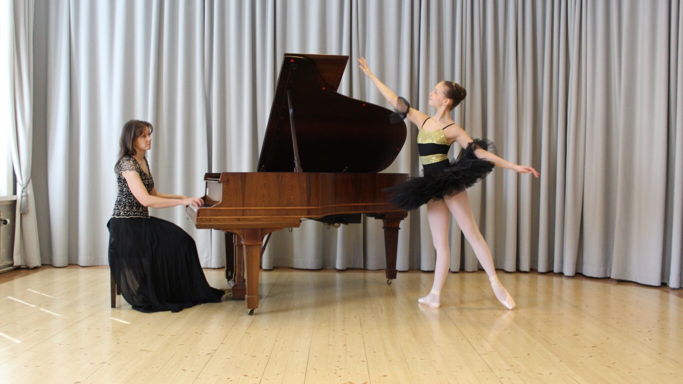 Kuvassa pianisti Angela Saarinen flyygelin ääressä sekä flyygelin vieressä balettitanssija Matilda Saarinen kimalaisasussa.