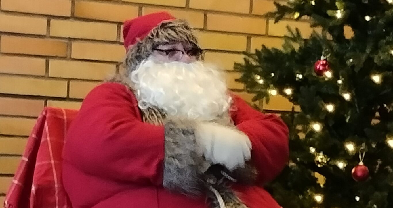 joulupukki istumassa joulukuusen vieressä.