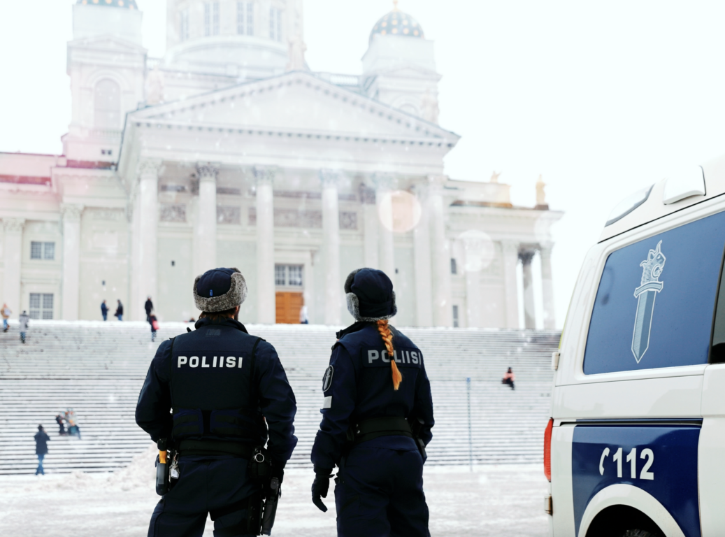 Kaksi poliisia seisoo selin Helsingin tuomiokirkon edessä talvella.