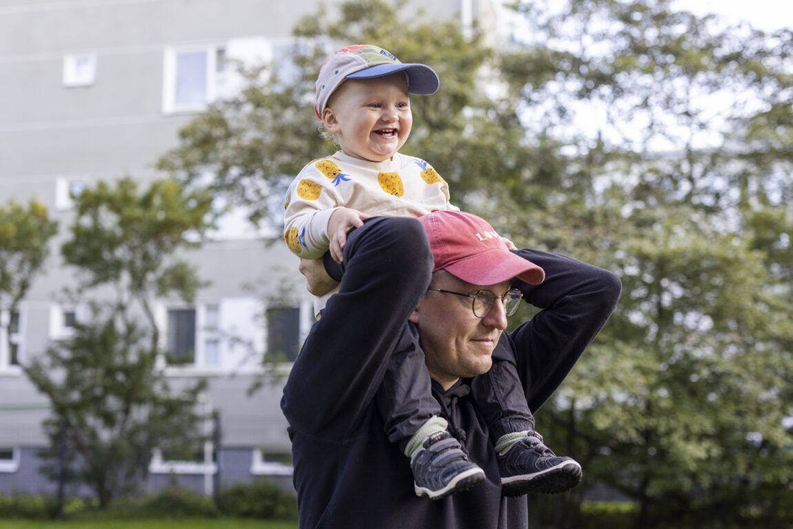 Pieni poika matkustaa isän harteilla.
