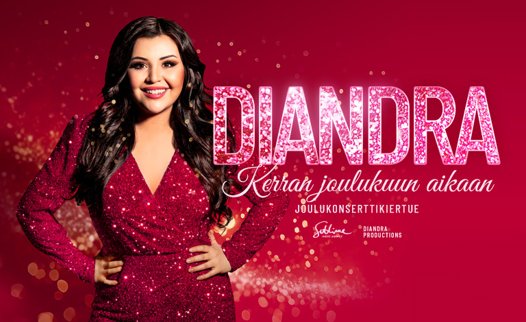 Diandra seisoo kädet lanteilla ja hymyilee.