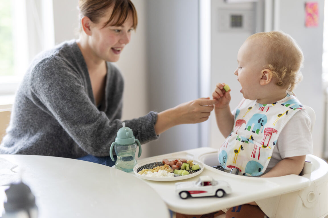 Äiti auttaa pientä lasta syömään