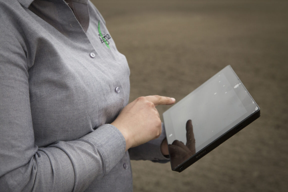 Nainen pellolla tabletti kädessä.