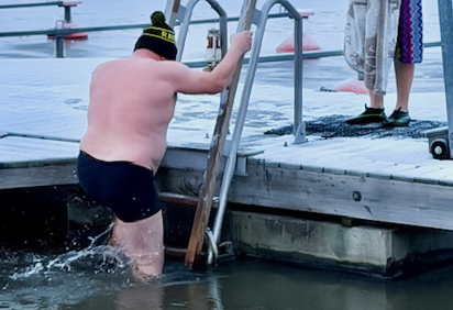 Mies laskeutuu laiturilta avantoon Mathildedalin talvisessa satamassa.