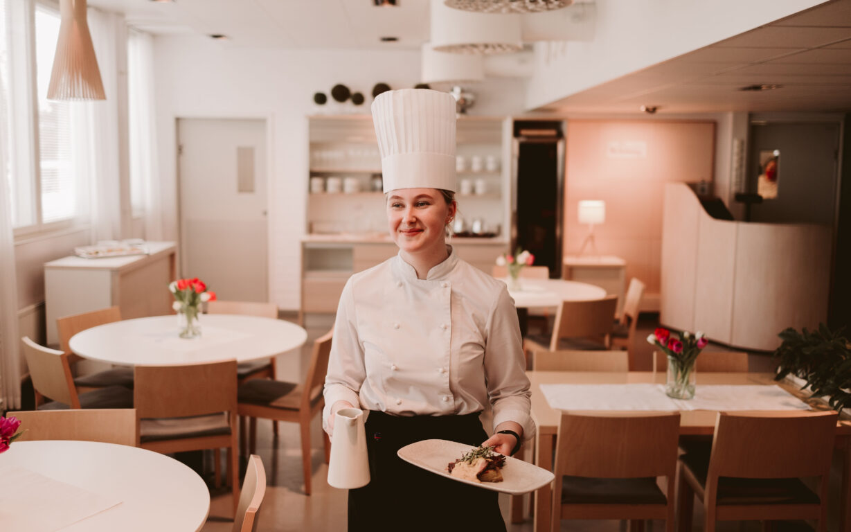 Ravintola- ja catering-alan opiskelija tarjoilee ruoka-annosta.