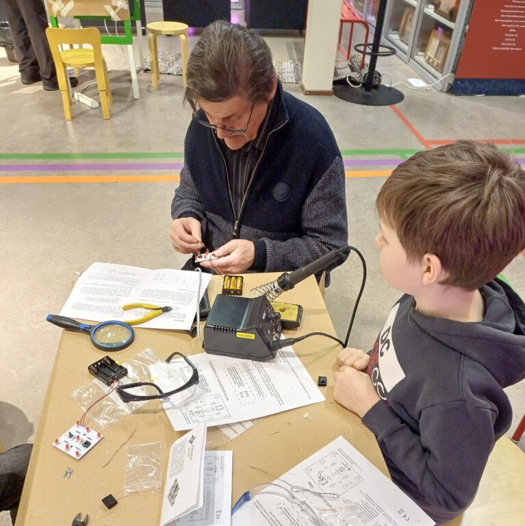 Aikuinen ja lapsi rakentavat yhdessä elektronista noppaa.