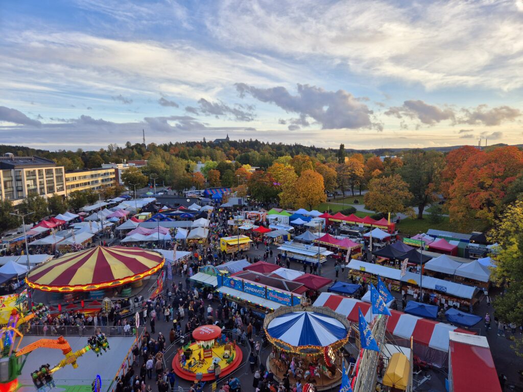Ylhäältä otettu kuva jossa näkyy värikkäitä markkinatelttojen kattoja ja paljon ihmisiä.