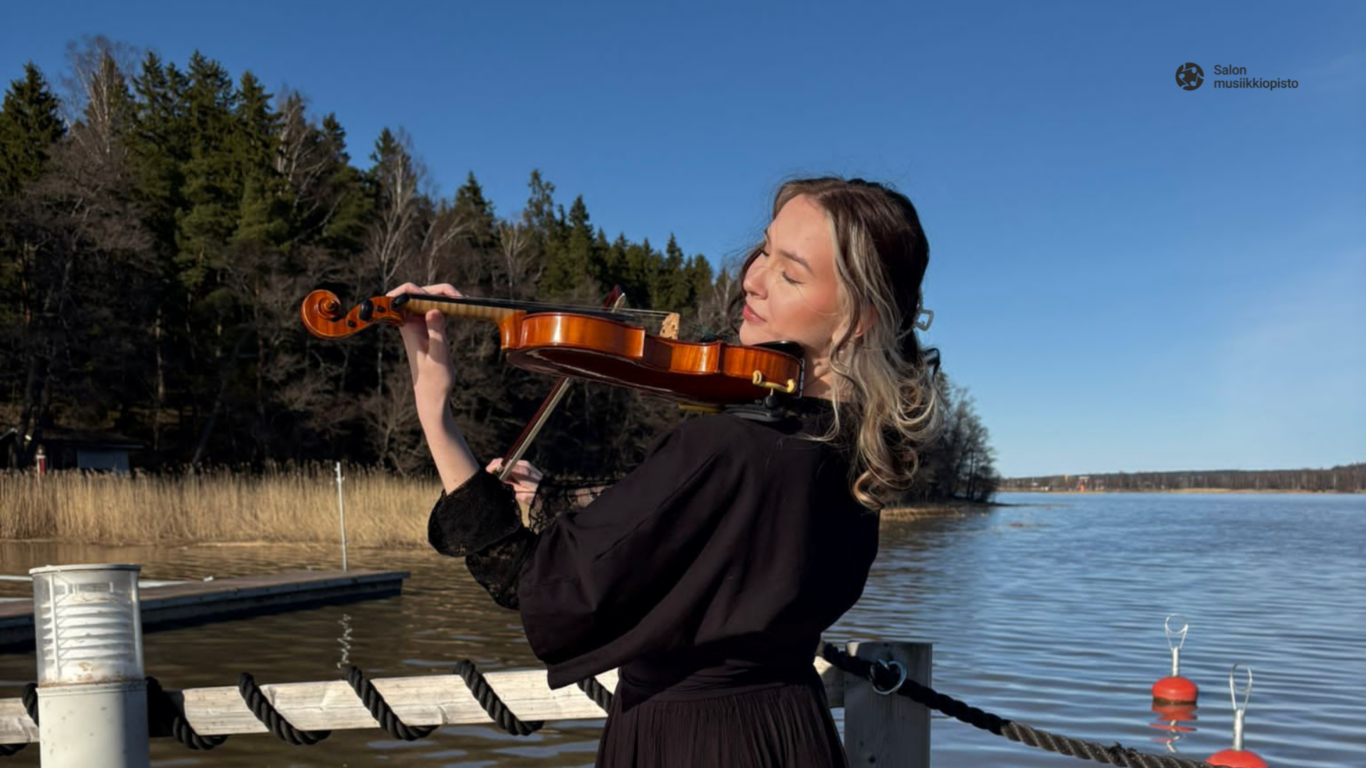 Tilda soittaa viulua Vuohensaaren laiturilla auringonpaisteessa.